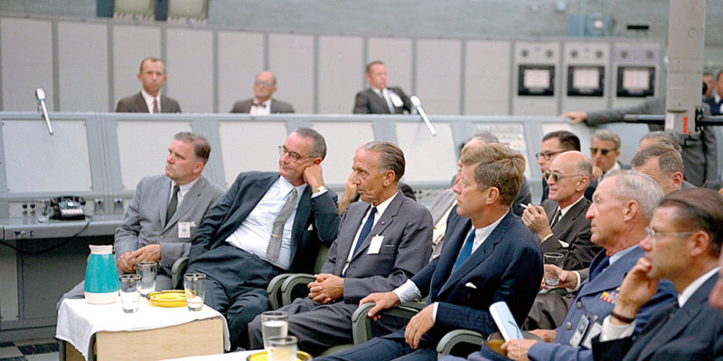 El presidente John F. Kennedy y el vicepresidente Lyndon B Johnson, durante una charla del director de lanzamientos de la NASA, Rocco Petrone (fuera de la imagen). Cabo Cañaveral, 11 de septiembre de 1962. Dominio público. NASA Commons.