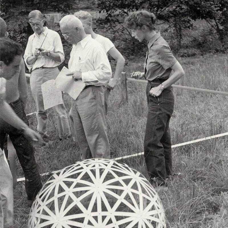 Richard Buckminster Fuller con sus alumnos en el Black Mountain College. Al fondo, con una pequeña cámara de fotos, puede verse a Josef Albers, profesor por entonces de aquella institución. Fotografía de Beaumont Newhall, 1948. State Archives of North Carolina Raleigh. Imagen de dominio público.